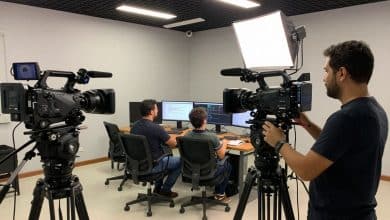 Equipe em um estúdio audiovisual prepara uma gravação com câmera, iluminação e monitor, representando diferentes carreiras do setor.