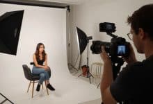 Fotógrafa trabalhando em estúdio com câmera profissional, iluminação e uma cena cuidadosamente composta, representando diferentes carreiras na fotografia.